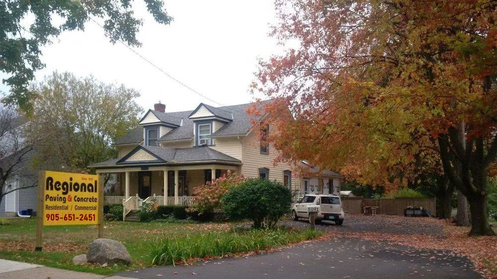 farm house with paved driveway and regional paving sign